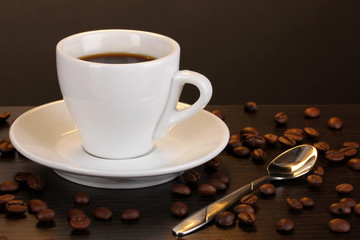 Cup of coffee on wooden table on brown background