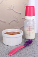 Baby food and milk on table on light background