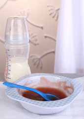 Baby food and milk on table on light background