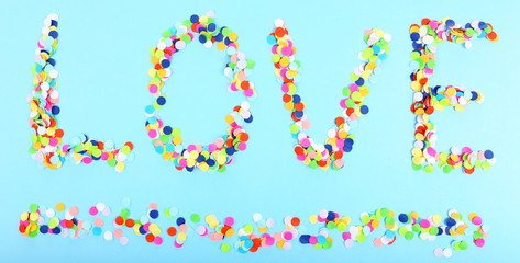 Word Love from confetti on blue background