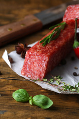 Tasty salami sausage and spices on wooden background