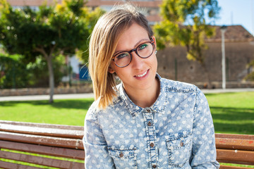 pretty young woman sitting on a park bench