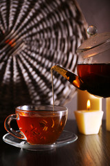 Tea pouring into glass cup on dark background