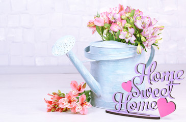 Beautiful bouquet of freesias in watering can in room