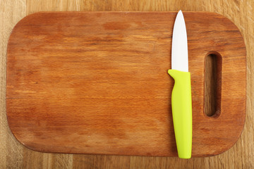 Kitchen knife and cutting board on wooden table