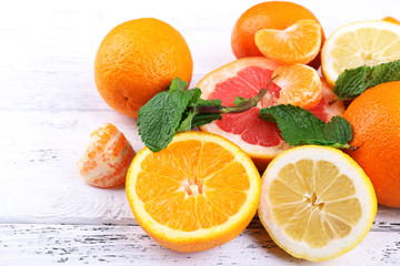 Fresh citrus fruits with green leaves on color wooden