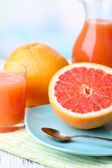 Half of grapefruit, glass jug with fresh juice and spoon