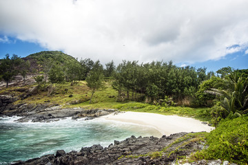 Small sandy beach between frozen lava flows of tropical volcanic