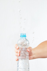 Female hand shaking a small bottle of fresh water with a splash