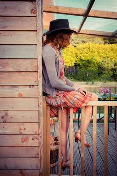 Woman wearing cowboy hat sitting on porch