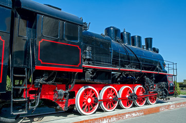 Old Russian (Soviet) steam locomotive on a pedestal on a backgro