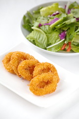 Deep fried calamari rings and green vegetables salad