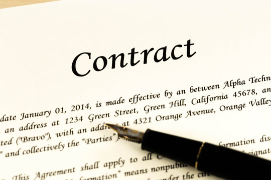 Business contract document on cream color paper with pen and gla