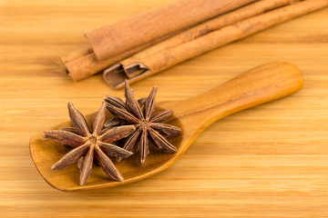 Anise stars in wooden spoon with cinnamon stick