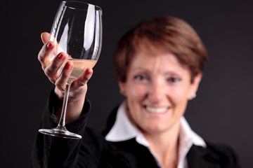 pretty old woman rising up a glass of wine (focus on hand)