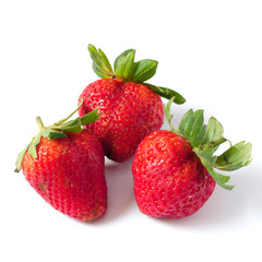 Three strawberries with leaves on a white