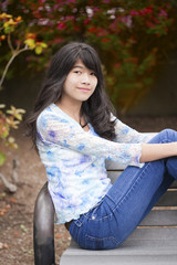 Young preteen girl sitting on park bench outdoors