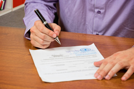 Close up of a male's hand, signing document.