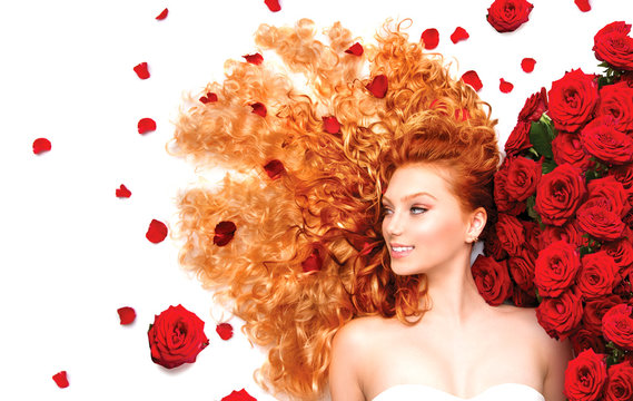 Beauty model girl with curly red hair and beautiful red roses