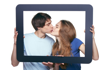 Fototapeta na wymiar In love couple holding tablet frame kissing