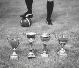 Several soccer trophies against football player.