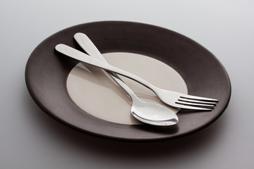 Plates with a silver fork and spoon isolated on gray background