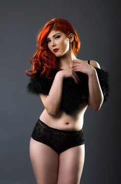 Curvy redhead in sexy lingerie isolated over gray background