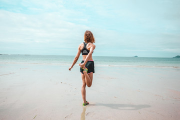 Fototapeta na wymiar Young woman stretching her leg on beach