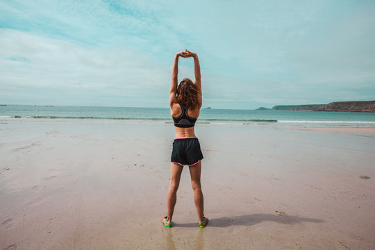 Young athletic woman stretching on the beach