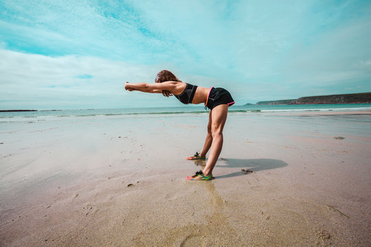Young athletic woman stretching on the beach