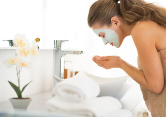 Obraz na płótnie Canvas Young woman wearing facial cosmetic mask washing face