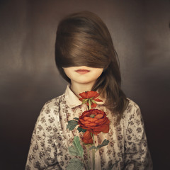 Girl with hair tied in front of her eyes, red rose in her hands and dotted blouse against a brown...