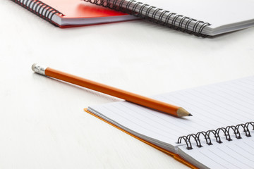orange pencil with notebooks