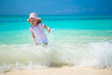 Fototapeta na wymiar Happy little girl playing in shallow water at exotic beach