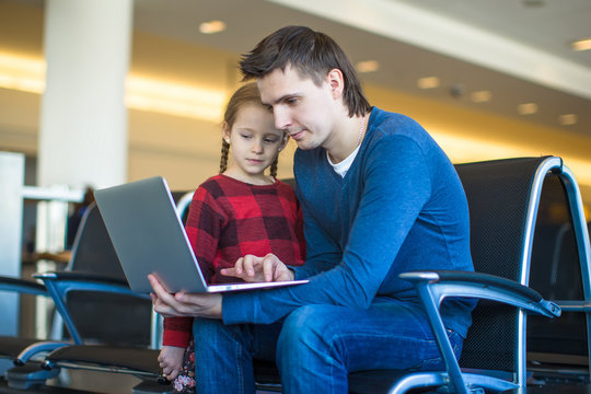 Father and little girl with laptop at the airport while waiting
