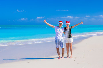 Young happy couple in red Santa hats enjoy summer vacation