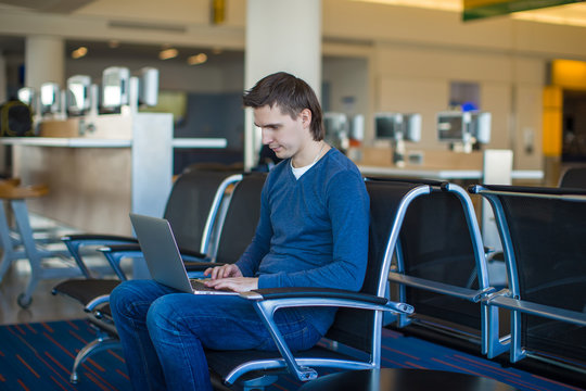 Young man with a laptop at the airport while waiting his flight