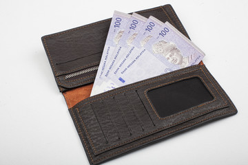 Ringgit Malaysia Currency Bank Notes in a leather wallet on a white background