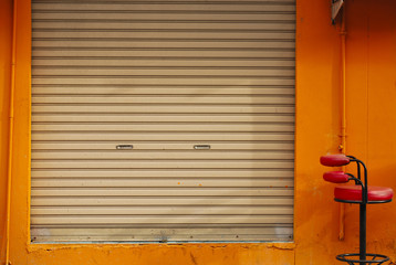 a shuttered roll up metal door with orange wall