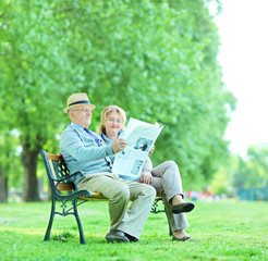Mature man and woman reading the news outdoors