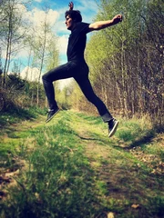 Zelfklevend Fotobehang young man jumping over forest path © ryszard filipowicz