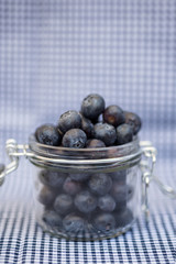 Fresh blueberries falling out of glass jar