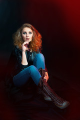 Beautiful young woman in a rock style sitting on the floor