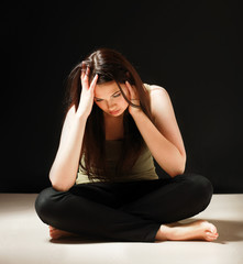 Depressed woman sitting on floor with eyes closed