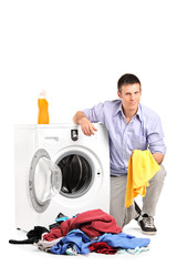 Young man emptying a washing machine