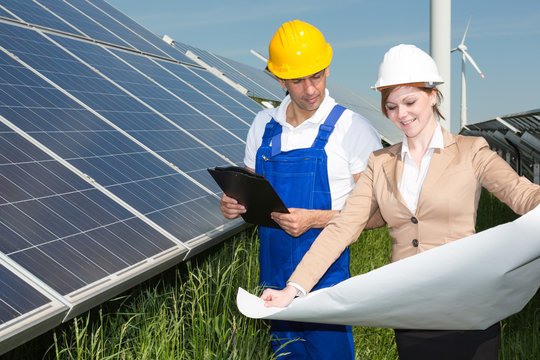 Two engineers look at construction plan of solar panels