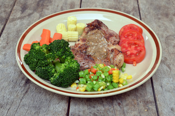 Grilled steaks, baked potatoes and vegetables on white plate on
