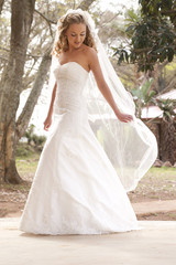 Young beautiful bride outdoors playing with veil