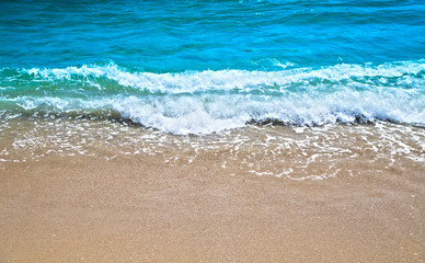 Fototapeta na wymiar Blue wave gently stroking the sandy shore.