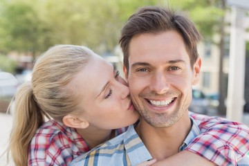 Fototapeta premium Young hip woman giving boyfriend kiss on the cheek